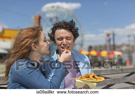 Romantic couple feeding each other chips at amusement park View Large Photo Image Stock Photography - Romantic couple feeding each other chips at amusement park. Fotosearch