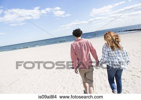 Romantic couple strolling hand in hand on beach View Large Photo Image Picture - Romantic couple strolling hand in hand on beach. Fotosearch