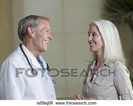 Stock Image - Senior male doctor reassuring mature woman patient. Fotosearch