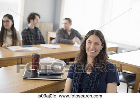 Teacher sitting at desk, portrait View Large Photo Image Picture - Teacher sitting at desk, portrait. Fotosearch
