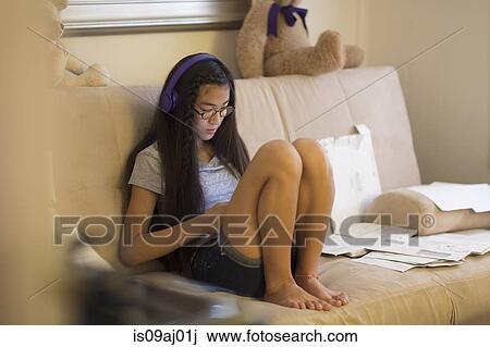 Teenage girl sitting on sofa, wearing headphones View Large Photo Image Stock Image - Teenage girl sitting on sofa, wearing headphones. Fotosearch