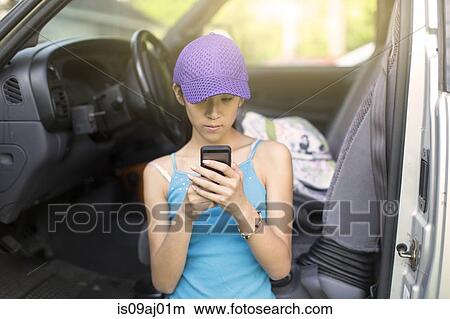 Teenage girl standing beside open car, using mobile phone View Large Photo Image Picture - Teenage girl standing beside open car, using mobile phone. Fotosearch