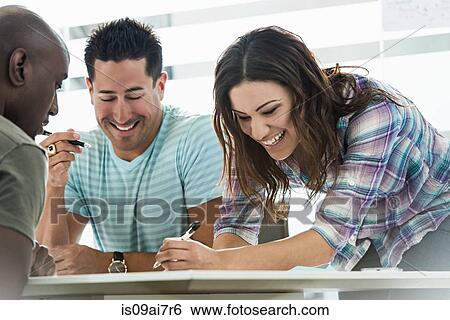Stock Photograph - Three business colleagues preparing ideas in office. Fotosearch