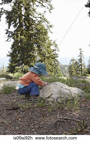 Toddler bending down to look at rock View Large Photo Image Stock Image - Toddler bending down to look at rock. Fotosearch