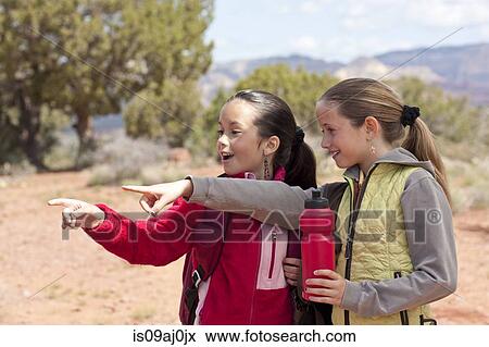 Two girls pointing and looking whilst hiking, Sedona, Arizona, USA View Large Photo Image Stock Photo - Two girls pointing and looking whilst hiking, Sedona, Arizona, USA. Fotosearch