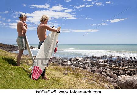 Two young male surfer friends watching sea View Large Photo Image Stock Photography - Two young male surfer friends watching sea. Fotosearch