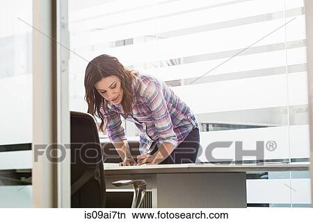 Picture - Young businesswoman busy in office. Fotosearch