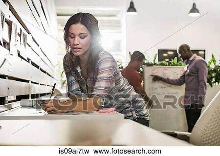 Stock Photo - Young businesswoman preparing paperwork in office. Fotosearch