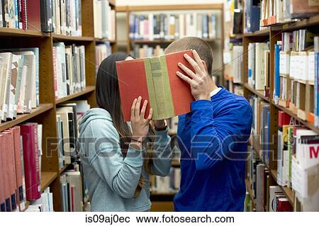 Young couple hiding behind book View Large Photo Image Stock Image - Young couple hiding behind book. Fotosearch