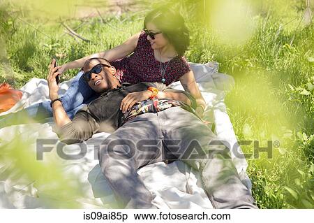 Young couple holding hands on picnic blanket in park View Large Photo Image Stock Photography - Young couple holding hands on picnic blanket in park. Fotosearch