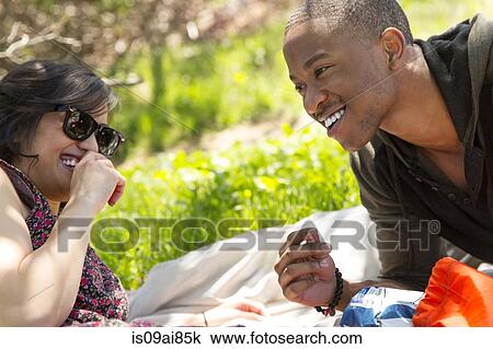 Young couple reclining on picnic blanket in park View Large Photo Image Stock Image - Young couple reclining on picnic blanket in park. Fotosearch