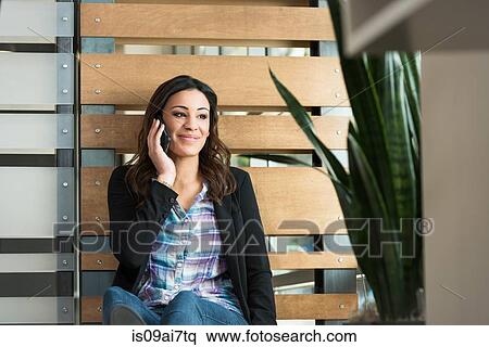 Young female office worker chatting on smartphone in office View Large Photo Image Stock Photography - Young female office worker chatting on smartphone in office. Fotosearch