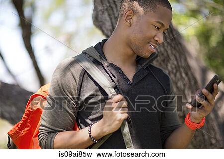 Young male hiker looking at smartphone View Large Photo Image Stock Photo - Young male hiker looking at smartphone. Fotosearch
