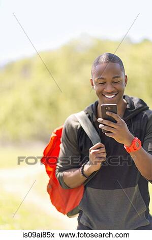 Young male hiker reading message on smartphone View Large Photo Image Stock Photo - Young male hiker reading message on smartphone. Fotosearch