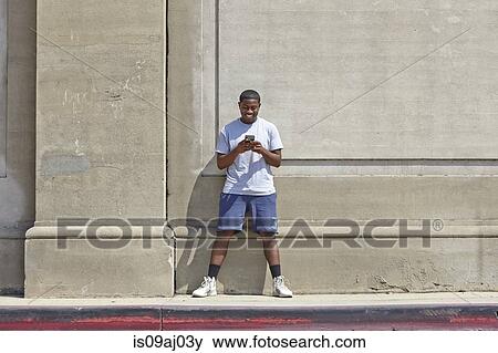 Young male runner texting on smartphone View Large Photo Image Stock Photo - Young male runner texting on smartphone. Fotosearch