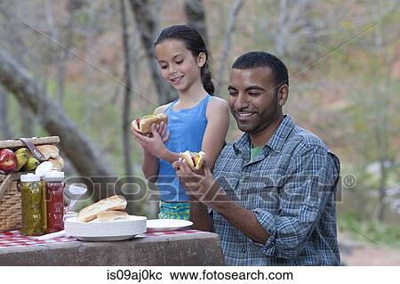 Stock Image - Young man and his daughter eating burgers on campsite, Sedona, Arizona, USA. Fotosearch