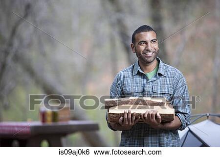 Young man carrying logs on campsite, Sedona, Arizona, USA View Large Photo Image Stock Photograph - Young man carrying logs on campsite, Sedona, Arizona, USA. Fotosearch