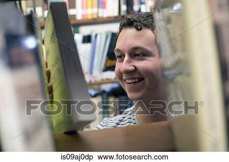 Young man choosing book in library View Large Photo Image Stock Photography - Young man choosing book in library. Fotosearch