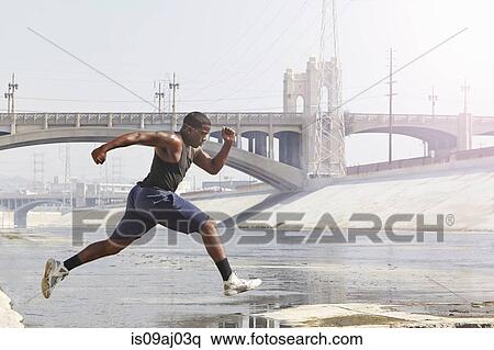 Stock Photography - Young man speed running and jumping from riverbank. Fotosearch