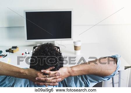 Young man taking break at office View Large Photo Image Stock Photograph - Young man taking break at office. Fotosearch