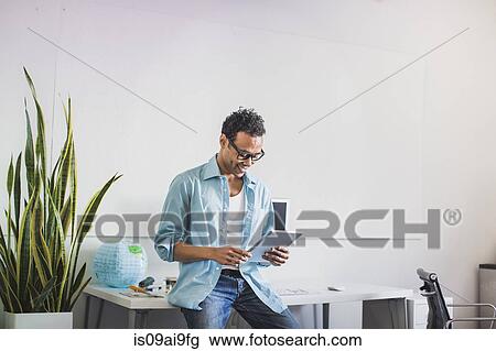 Young man using digital tablet at office View Large Photo Image Stock Image - Young man using digital tablet at office. Fotosearch