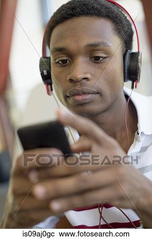 Stock Image - Young man using mp3 player. Fotosearch