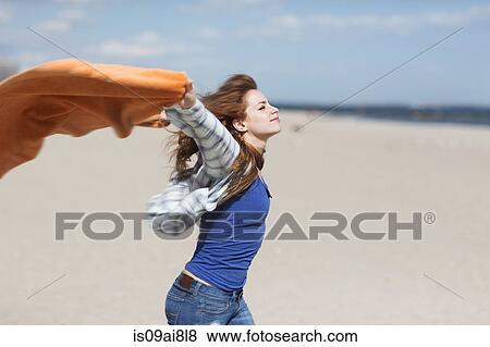 Young woman holding up blanket on windy beach View Large Photo Image Stock Photo - Young woman holding up blanket on windy beach. Fotosearch