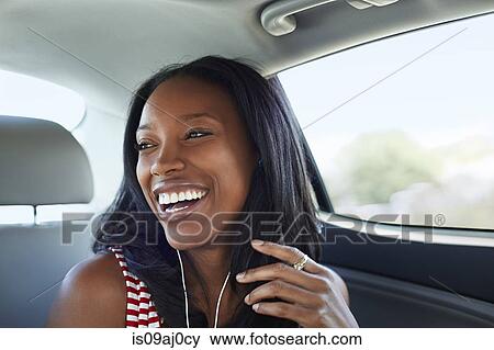 Stock Photo - Young woman laughing car backseat. Fotosearch