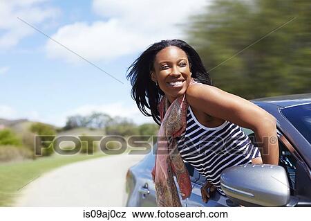 Young woman leaning out of moving car window View Large Photo Image Stock Photo - Young woman leaning out of moving car window. Fotosearch