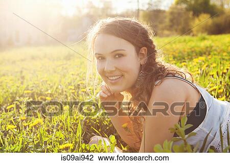 Stock Image - Young woman lying in field. Fotosearch