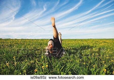 Young woman lying on grass with legs raised View Large Photo Image Stock Photo - Young woman lying on grass with legs raised. Fotosearch