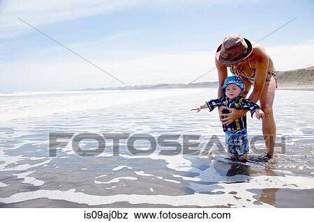 Young woman paddling in sea with baby son View Large Photo Image Stock Photo - Young woman paddling in sea with baby son. Fotosearch