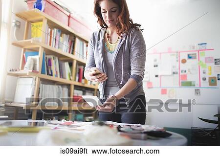 Stock Photograph - Young woman photographing documents with smartphone. Fotosearch