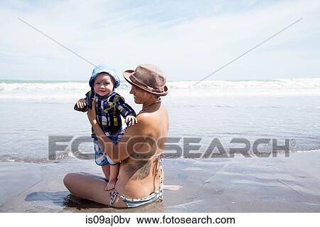 Young woman sitting in sea with baby son View Large Photo Image Stock Photo - Young woman sitting in sea with baby son. Fotosearch