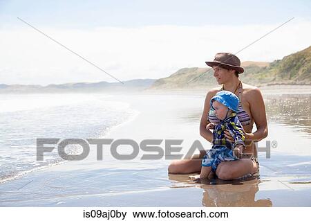 Young woman sitting on beach with baby son View Large Photo Image Stock Photo - Young woman sitting on beach with baby son. Fotosearch