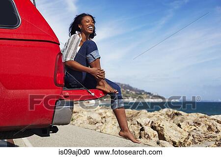 Young woman sitting on car hood, Malibu, California, USA View Large Photo Image Stock Image - Young woman sitting on car hood, Malibu, California, USA. Fotosearch