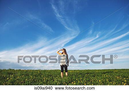 Young woman standing in field View Large Photo Image Stock Image - Young woman standing in field. Fotosearch