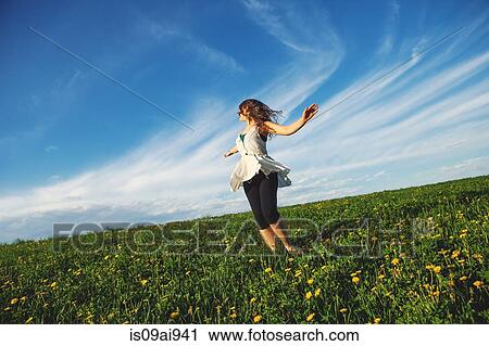 Stock Image - Young woman standing in field. Fotosearch