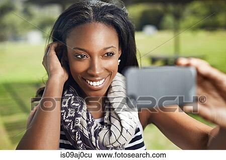 Stock Photograph - Young woman taking self portrait on smartphone. Fotosearch