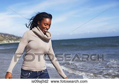 Stock Image - Young woman walking on beach, Malibu, California, USA. Fotosearch