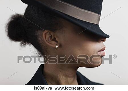 Stock Image - Young woman wearing hat covering eyes. Fotosearch