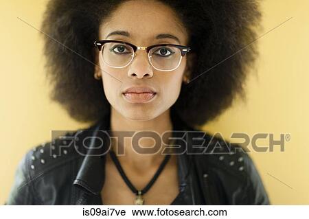 Stock Image - Young woman wearing leather jacket and eyeglasses, studio shot. Fotosearch