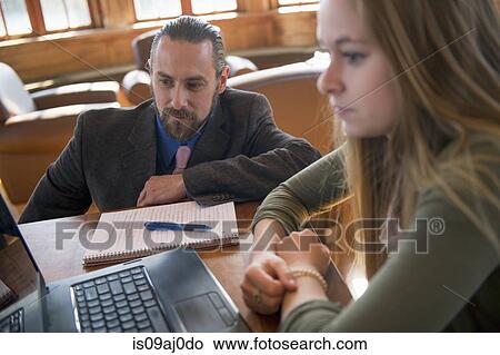 Picture - Young woman with laptop, teacher watching. Fotosearch