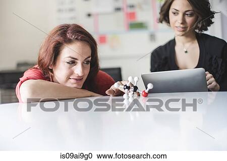 Stock Image - Young women discussing molecular model of Ethanol molecule. Fotosearch