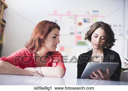 Young women discussing, using digital tablet View Large Photo Image Stock Image - Young women discussing, using digital tablet. Fotosearch
