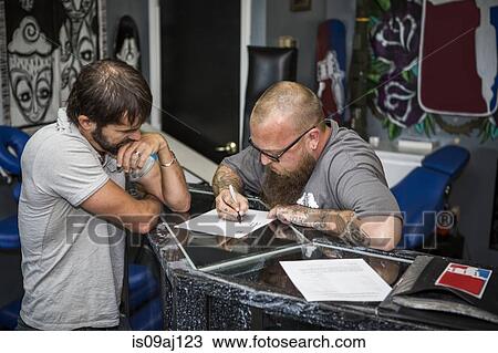 Artist drawing up tattoo ideas with a client View Large Photo Image Stock Image - Artist drawing up tattoo ideas with a client. Fotosearch
