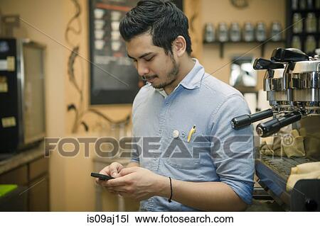 Barista texting on smartphone in cafe View Large Photo Image Stock Image - Barista texting on smartphone in cafe. Fotosearch