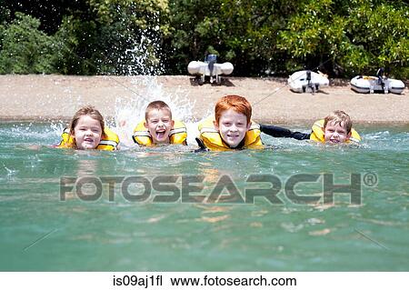 Stock Image - Brothers and sister in a row swimming in sea. Fotosearch