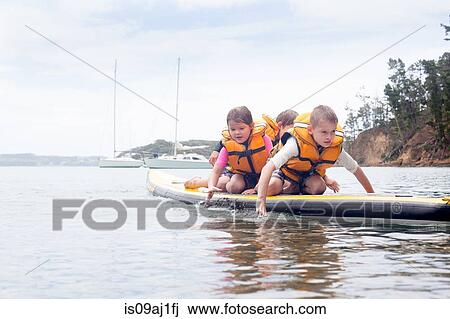 Brothers and sister paddleboarding on knees at sea View Large Photo Image Stock Image - Brothers and sister paddleboarding on knees at sea. Fotosearch