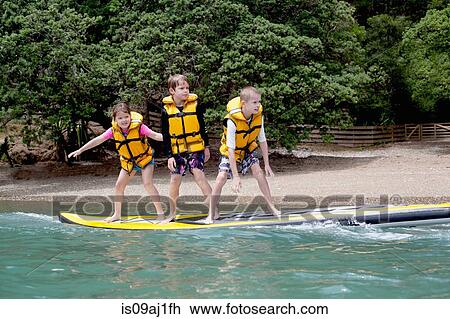 Brothers and sister standing on paddleboard at sea View Large Photo Image Stock Image - Brothers and sister standing on paddleboard at sea. Fotosearch